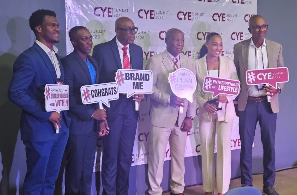 A group photo of the panel speakers and participants holding entrepreneurship signs on stage at the CYE Summit 2026.